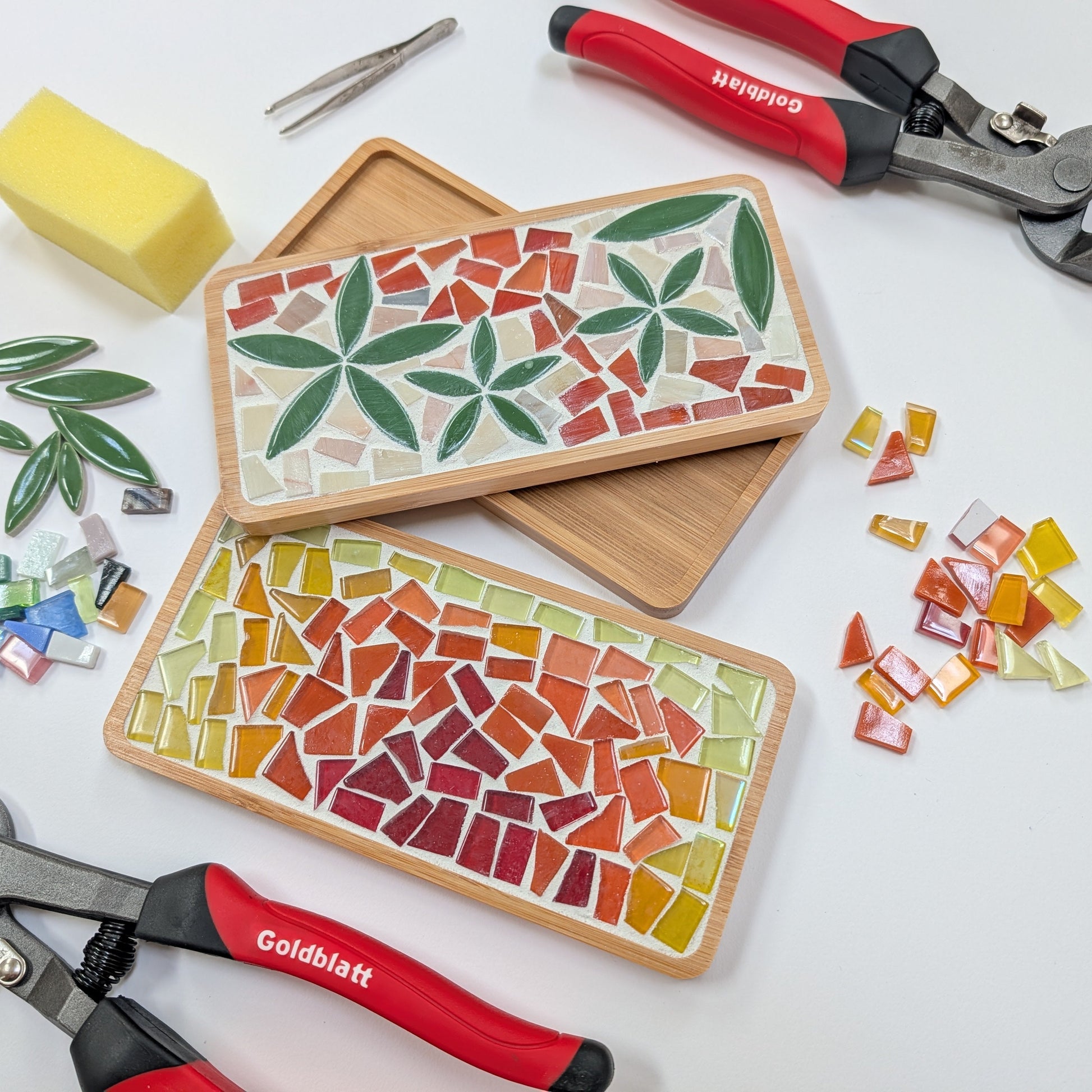 Two mosaic art pieces on wooden boards with tools and materials on a white background. Wendy Creative art class in Langford BC